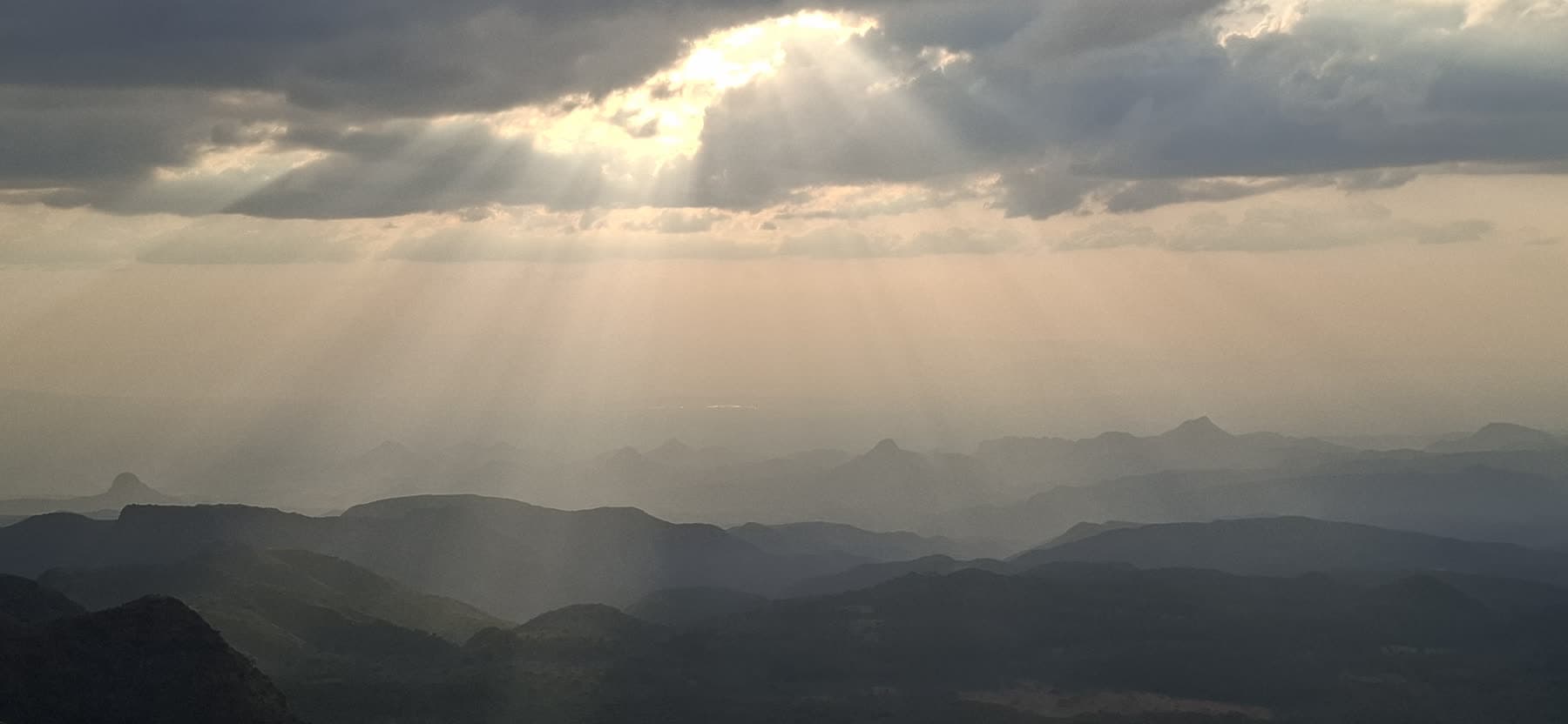 Sunbeams breaking through clouds over the green Malaso escarpment