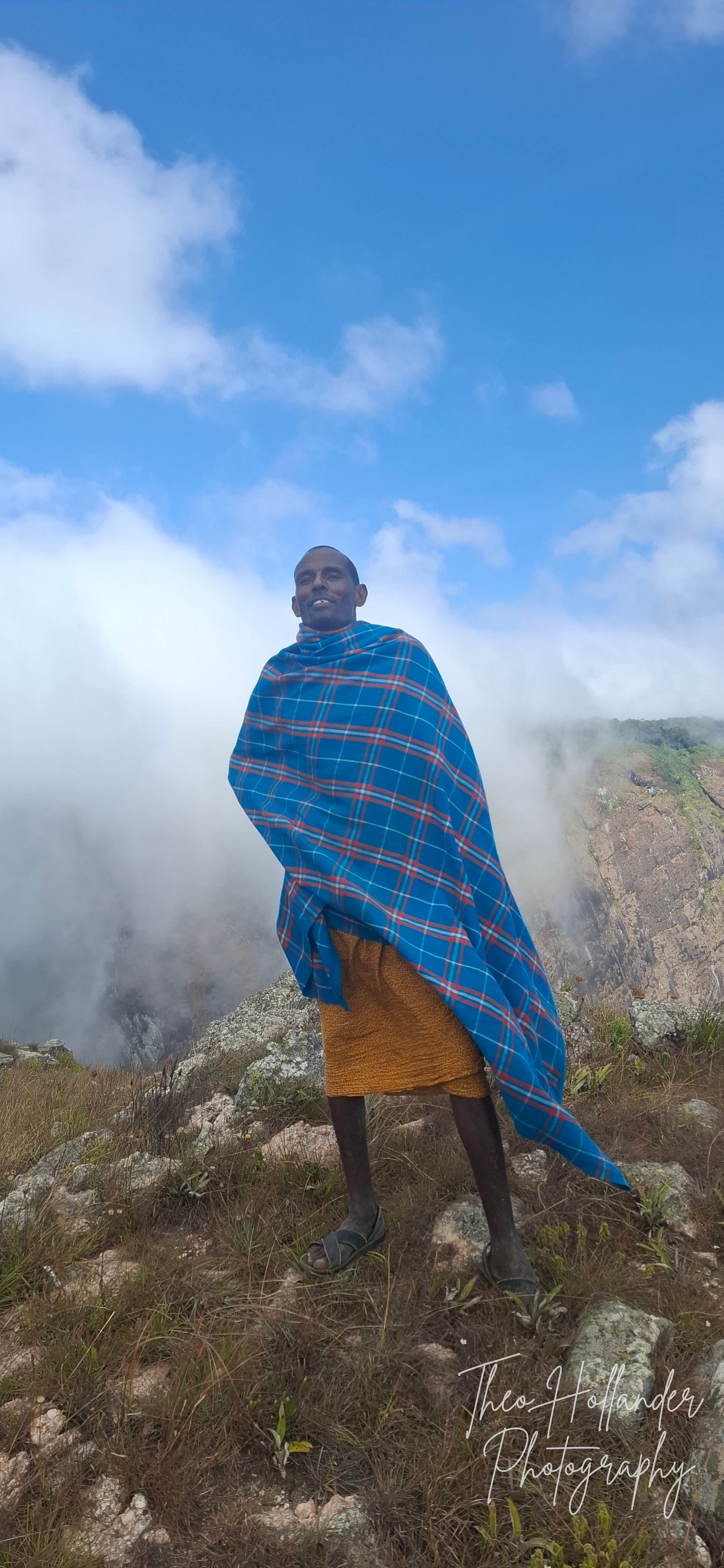 A Samburu man wrapped in a traditional shuka as clouds pour over the ridge behind him