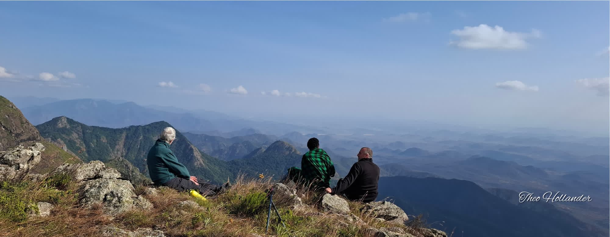 Travellers resting on a Ndoto Mountains ridge with their Samburu guides, looking out over the valley